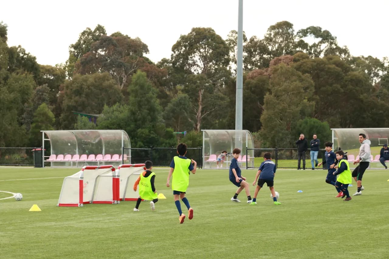 Astra United youth players in kit and bibs training in a small-sided session with coaches on the Darebin pitch