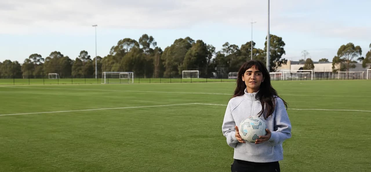 Astra United girls' program player holding a football on the pitch at Darebin International Sports Centre